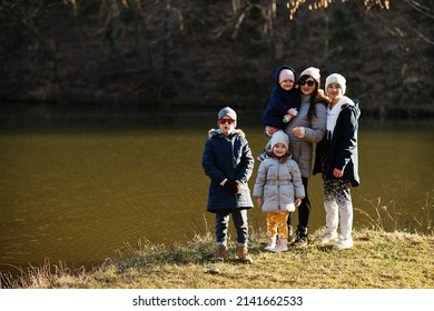 Mother With Four Kids In Pound At Early Spring Park.