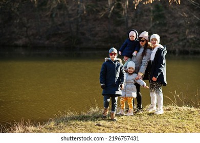 Mother With Four Kids In Pound At Early Spring Park.