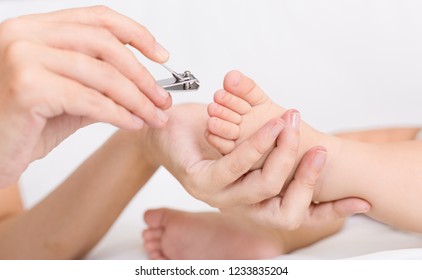 Mother Gently Clipping Baby's Toenails With Nipper, Closeup