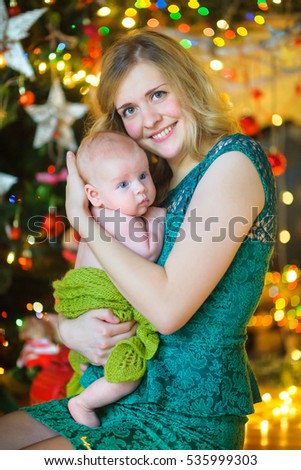 Mother gently embraces and presses to a breast of the newborn son. A happy family waiting for a holiday