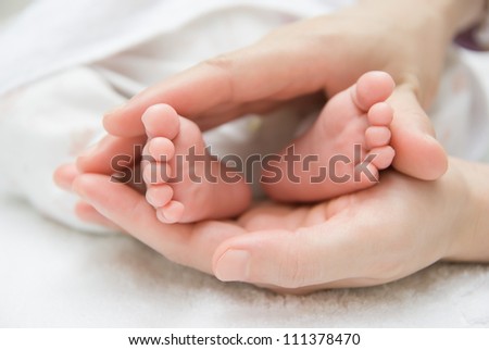 mother gently hold a newborn baby's feet