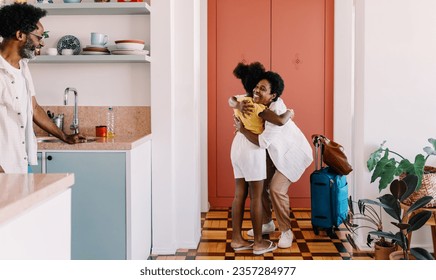 Mother getting welcomed home by her daughter at the door, sharing a  hug that symbolizes the joy of reunion and the love of family. Happy mom arriving home to her little girl's arms after a trip.
