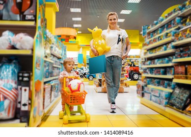 Mother With Girl Buying A Lot Of Toys In Store