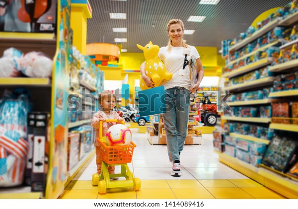 Mother with girl\
buying a lot of toys in\
store