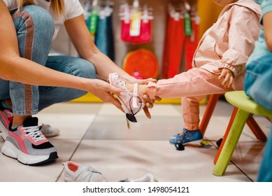 Mother With Girl Choosing Shoes In Kids Store