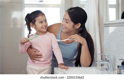 Mother With Girl Learning To Brush Teeth With Toothbrush Together In Bathroom For Oral Or Dental Wellness. Happy, Love And Care Mom Teaching Child Or Kid About Dentistry And Cleaning Mouth In Morning