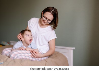 Mother gives a massage to child with cerebral palsy. Rehabilitation therapy at home. Developing leisure activities. Disabled child epilepsy autism. Moments of life. Lifestyle. Hope support love family