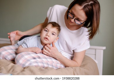 Mother gives a massage to child with cerebral palsy. Rehabilitation therapy at home. Developing leisure activities. Disabled child epilepsy autism. Moments of life. Lifestyle. Hope support love family