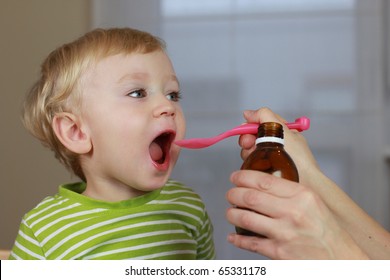 Mother Giving 2 Years Old Baby Boy Medicine, Cough Syrup On A Spoon. Sick Child.