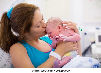 Mother Giving Birth To A Baby. Newborn Baby In Delivery Room. Mom Holding Her New Born Child After Labor. Female Pregnant Patient In A Modern Hospital. Parent And Infant First Moments Of Bonding.