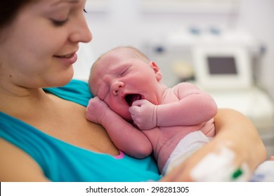 Mother Giving Birth To A Baby. Newborn Baby In Delivery Room. Mom Holding Her New Born Child After Labor. Female Pregnant Patient In A Modern Hospital. Parent And Infant First Moments Of Bonding.