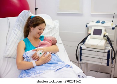 Mother Giving Birth To A Baby. Newborn Baby In Delivery Room. Mom Holding Her New Born Child After Labor. Female Pregnant Patient In A Modern Hospital. Parent And Infant First Moments Of Bonding.