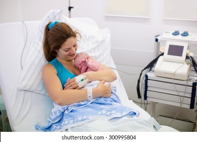 Mother Giving Birth To A Baby. Newborn Baby In Delivery Room. Mom Holding Her New Born Child After Labor. Female Pregnant Patient In A Modern Hospital. Parent And Infant First Moments Of Bonding.