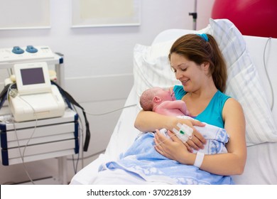 Mother Giving Birth To A Baby. Newborn Baby In Delivery Room. Mom Holding Her New Born Child After Labor. Female Pregnant Patient In A Modern Hospital. Parent And Infant First Moments Of Bonding.