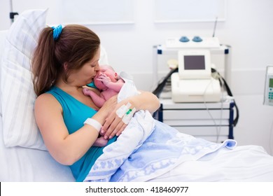 Mother Giving Birth To A Baby. Newborn Baby In Delivery Room. Mom Holding Her New Born Child After Labor. Female Pregnant Patient In A Modern Hospital. Parent And Infant First Moments Of Bonding.