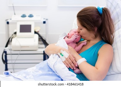 Mother Giving Birth To A Baby. Newborn Baby In Delivery Room. Mom Holding Her New Born Child After Labor. Female Pregnant Patient In A Modern Hospital. Parent And Infant First Moments Of Bonding.