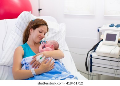 Mother Giving Birth To A Baby. Newborn Baby In Delivery Room. Mom Holding Her New Born Child After Labor. Female Pregnant Patient In A Modern Hospital. Parent And Infant First Moments Of Bonding.