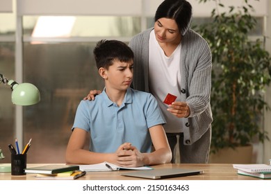 Mother giving condom to her teenage son while he doing homework at home.