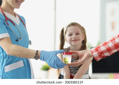 Mother giving doctor jar of urine in front of child at clinic closeup