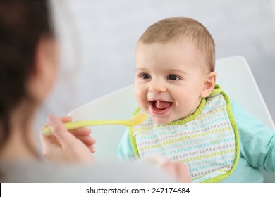 Mother Giving Fruit Sauce To Baby Boy