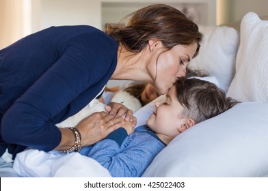 Mother giving good night kiss to sleeping son. Lovely mother putting son to bed. Happy young loving mother kisses son on forehead.
 - Powered by Shutterstock