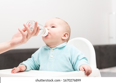 Mother Giving Her Baby Child Son Water To Drink From Bottle At Home