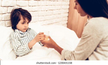 Mother Giving Medicine To Sick Son Lying Bed. Caring Mom Giving Sick Boy Pills. Worried Mother Giving Glass Of Water To Ill Kid. Hospital Concept. Healthy Concept. Parent Concept.