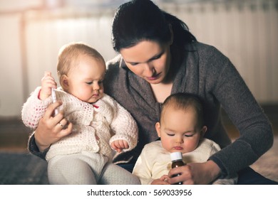 Mother Giving Medicine To Twins Babies