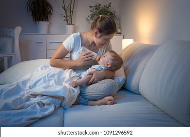 Mother Giving Milk To Her Hungry Baby At Night