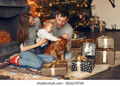 Mother In A Gray Sweater. Family With Christmas Gifts. People Near Fireplace. Family With Dog.