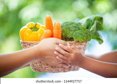 Mother Hand And Child Hand Holding Basket Of Vegetables Together