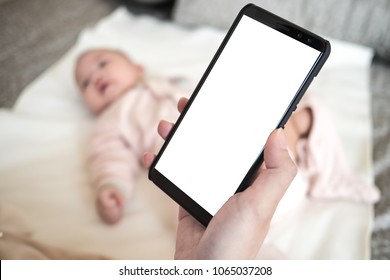 Mother Hand Hold Mobile Phone With Blurred Baby Background: Mock Up Mobile App For Mom And Baby