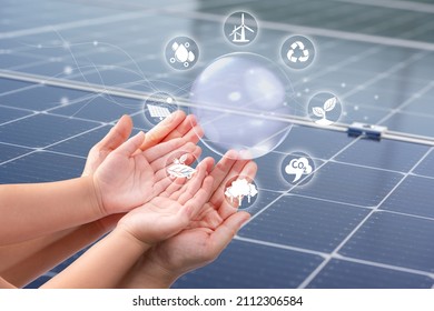 Mother And Child’s Hand Holding Solar Cell And Green Plant Icon Over Solar Panels On Solar Cell System, Solar Cell Energy, Clean Energy, Ecology Concept.