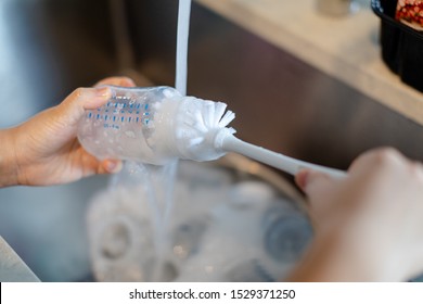 Mother Hand Washing Baby Milk Bottle With Brush. Selective Focus.