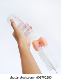 Mother Hand Washing Baby Milk Bottle By Bottle Brush On White Background