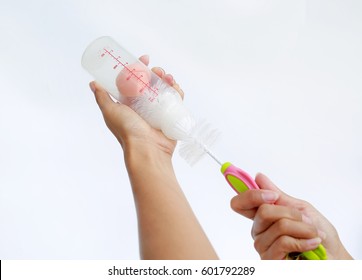 Mother Hand Washing Baby Milk Bottle By Bottle Brush On White Background