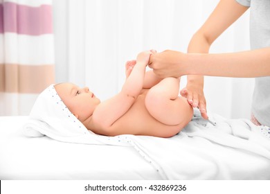 Mother hands applying cream on little baby body in room