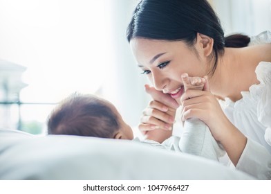 Mother hands holding newborn baby feet. Close up portrait of beautiful young asian or caucasian mother with newborn baby day. Healthcare and medical love lifestyle mother's day concept