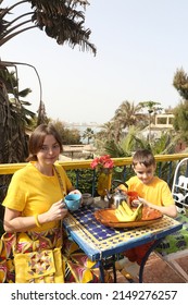 Mother Has Breakfast With Her Son On Ngor Island, Senegal, Africa. Table Layout, Table Setting For Breakfast. Woman With Child, Kid And Food. Tourist People Has Breakfast In Senegal, Africa. Banana