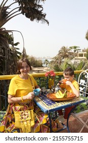 Mother Has Breakfast With Her Son On Ngor Island, Senegal, Africa. Table Layout, Table Setting For Breakfast. Woman With Child, Kid And Food. Tourist People Has Breakfast In Senegal, Africa. Banana