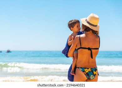 Mother With Hat With Her Son Embraced By The Sea, Algarve Beach, Albufeira. Portugal