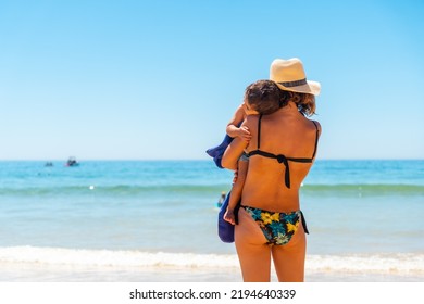 Mother With Hat With Her Son Embraced By The Sea, Algarve Beach, Albufeira. Portugal