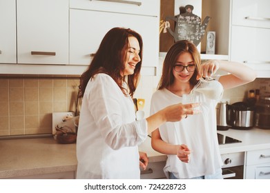 mother having breakfast with teen daughter at home in modern white kitchen. Casual lifestyle in real life interior