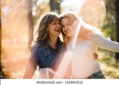 Mother having great time with her adult daughter outdoor in park - flare visible