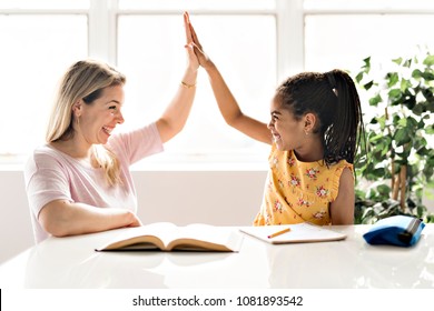 mother help Black girl doing homework at home