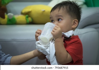 Mother Helping Child Drinking Milk From Plastic Cup With Napkin Absorp A Spilled Milk From Mouh