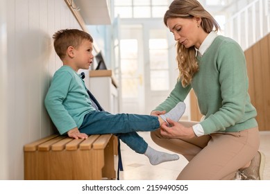 Mother Helping A Child To Put His Indoor Shoes On In A Beautiful Daycare Educational Center