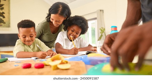 Mother Helping Children With Homework Sitting At Table As Father Makes Packed Lunch - Powered by Shutterstock