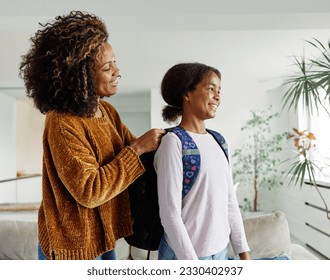 Mother helping daughter to get ready for school, helping her with backpack and books,hugging and leaving home  - Powered by Shutterstock