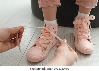 Mother helping daughter to tie shoe laces at home, closeup - Powered by Shutterstock